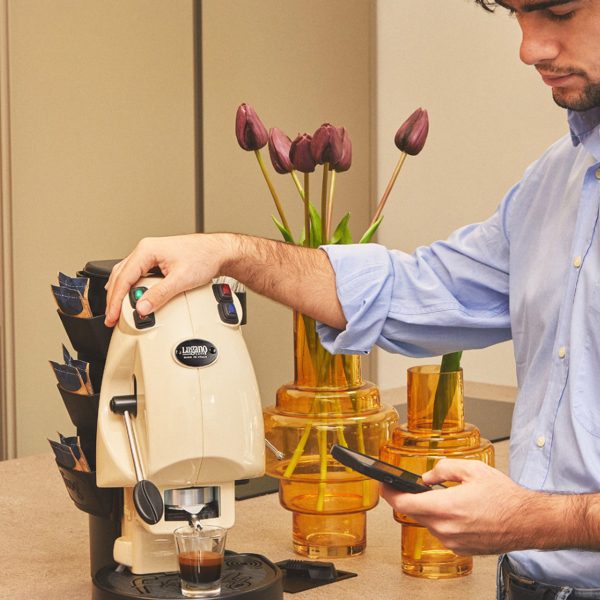 An Italian man using Lugano Uno espresso Machine while on the phone
